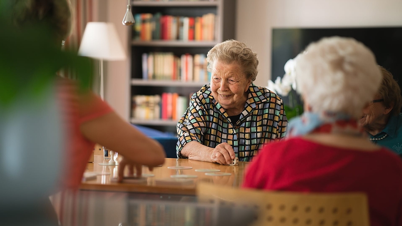 Bewohnerin hat sich über Kostenübernahme Pflegeheim informiert und spielt nun Gesellschaftsspiele im Landhaus Pflege & Wohnen