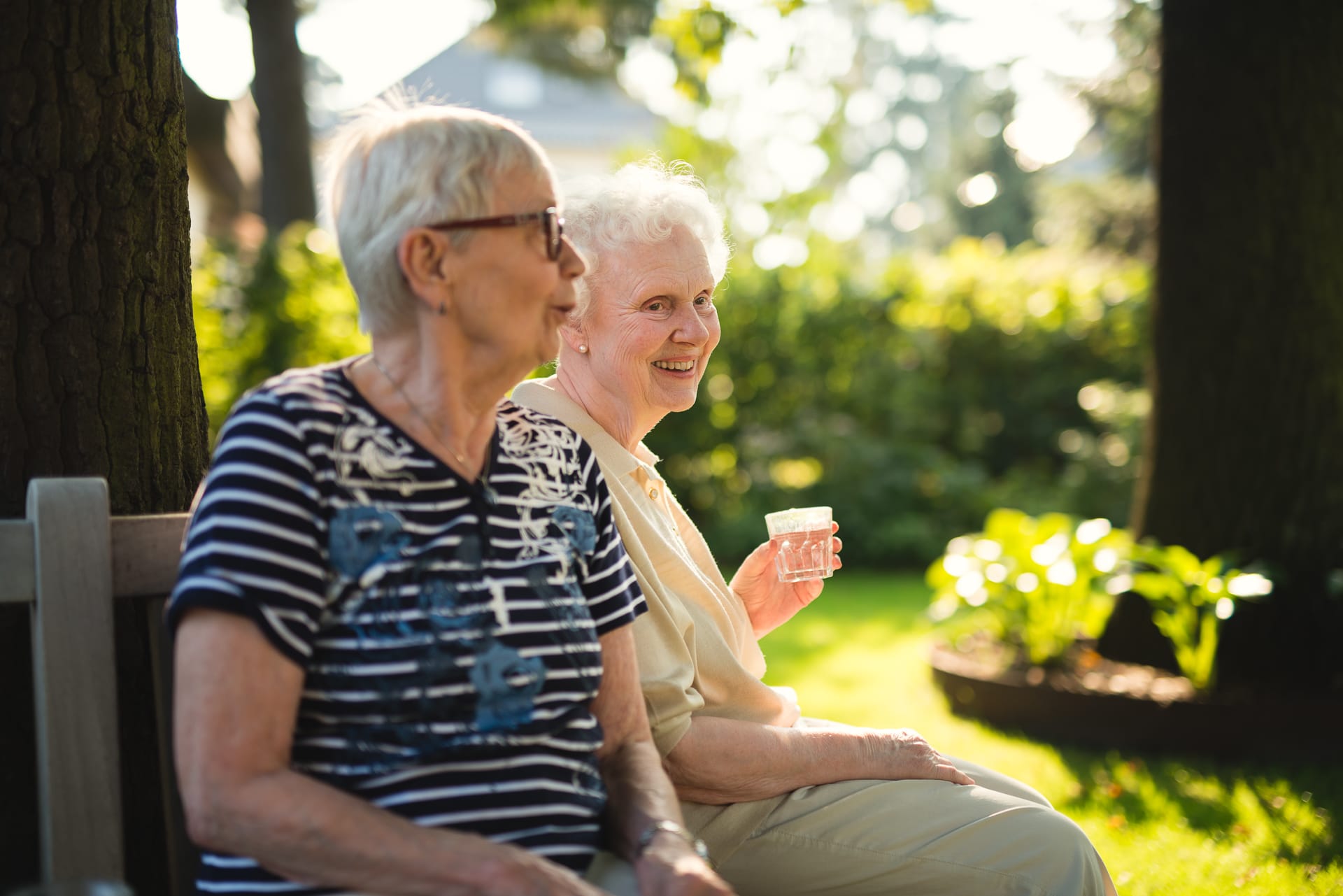 Zwei Frauen sitzen auf Bank im Garten des Pflegeheims Landhaus Pflege und Wohnen