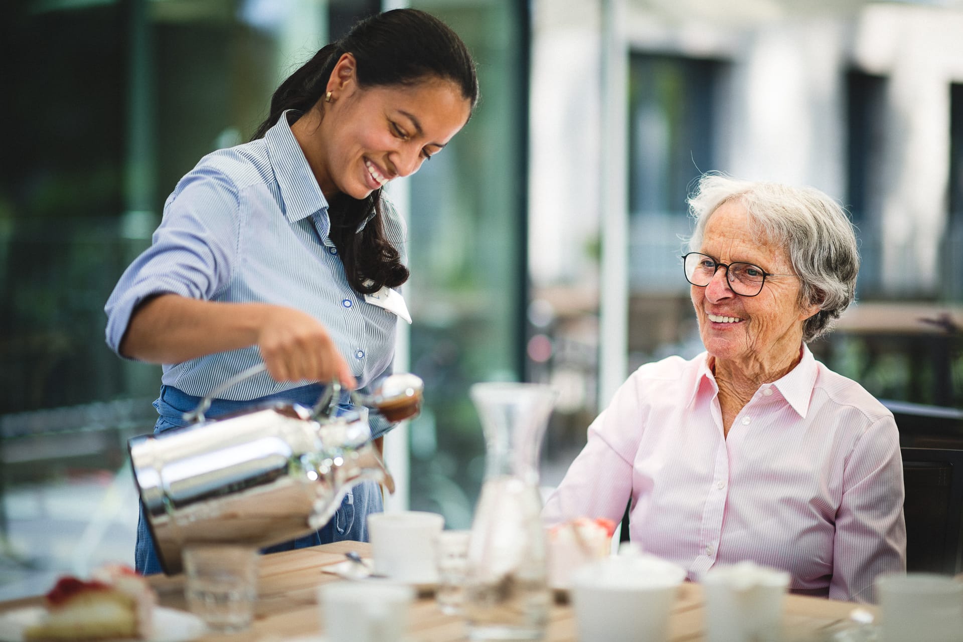 Servicekraft und Pflegerin lachen bei Kaffee und Kuchen im Pflegeheim in Hannover Landhaus Pflege und Wohnen