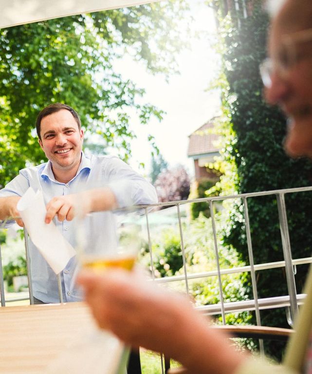 Johannes Tilgner beim Gespräch mit Bewohnern auf der Terrasse im Pflegeheim in Hannover Landhaus Pflege und Wohnen