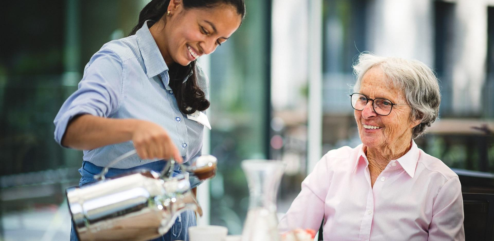 Servicekraft und Pflegerin lachen bei Kaffee und Kuchen im Pflegeheim in Hannover Landhaus Pflege und Wohnen