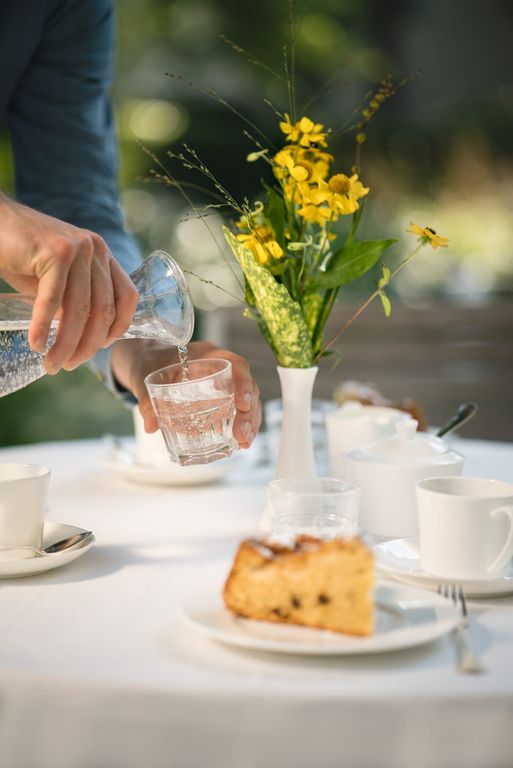 Tisch im Garten Mann schenkt Wasser ein Pflegeheim in Hannover Landhaus Pflege und Wohnen