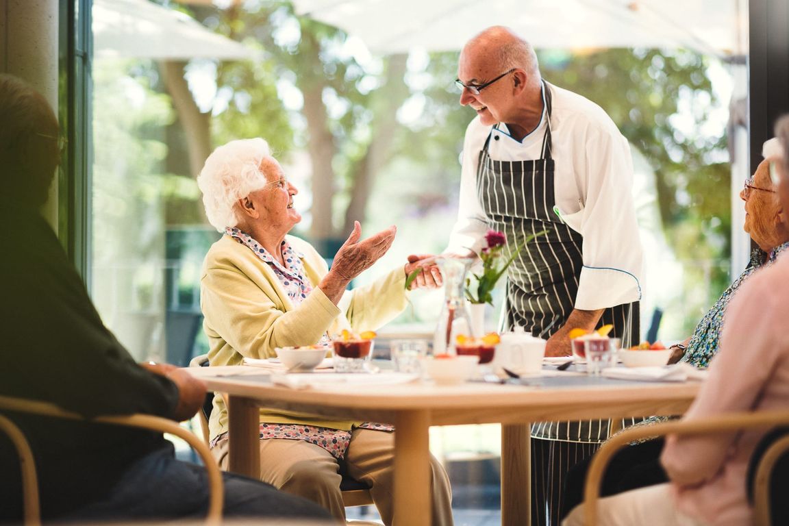 Koch und ältere Frau unterhalten sich im Restaurant im Pflegeheim in Hannover Landhaus Pflege und Wohnen