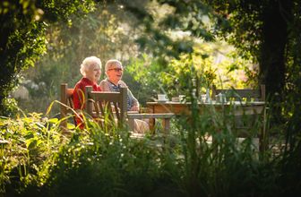 Zwei Frauen sitzen auf einer Bank im Garten des Landhaus Pflegeheim Hannover