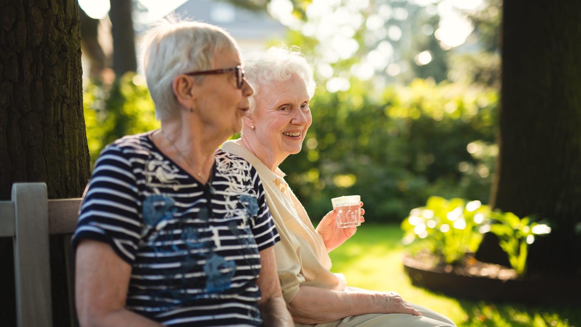 Zwei Frauen sitzen auf Bank im Garten des Pflegeheims Landhaus Pflege und Wohnen