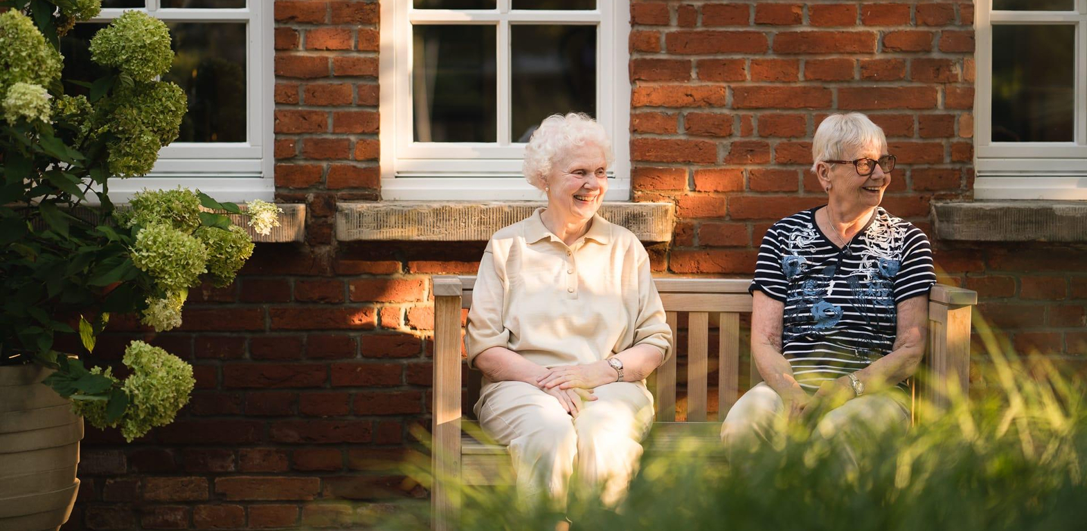 Zwei Bewohnerinnen sitzen draußen auf einer Bank beim Landhaus Pflege und Wohnen Hannover