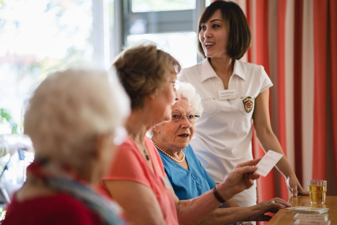 Frauen, Bewohner und Pflegekräfte, spielen im Gruppenraum Spiele moderne Altenpflege Hannover	